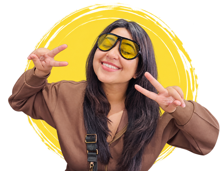 Geetika Khurana smiling in yellow sunglasses, making peace signs with both hands, against a yellow brushstroke circle.